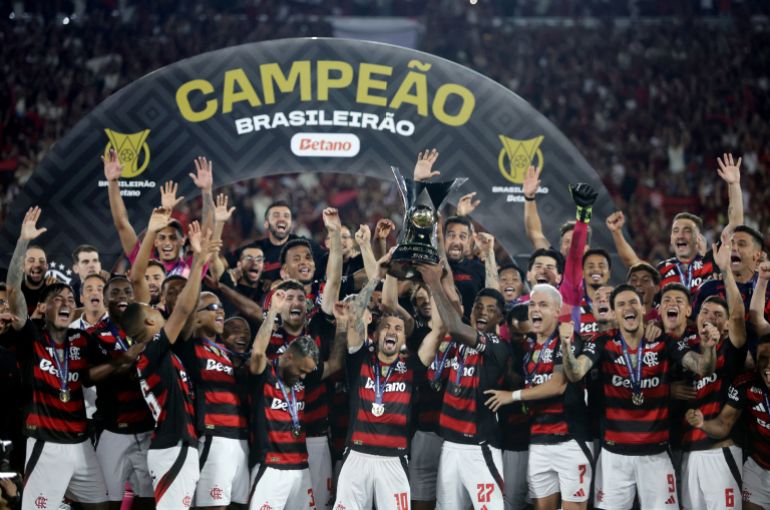 Georgiana de Arascaeta y Bruno Henrique del Flamengo levantan el trofeo mientras celebran con sus compañeros tras ganar la liga Brasileiro.