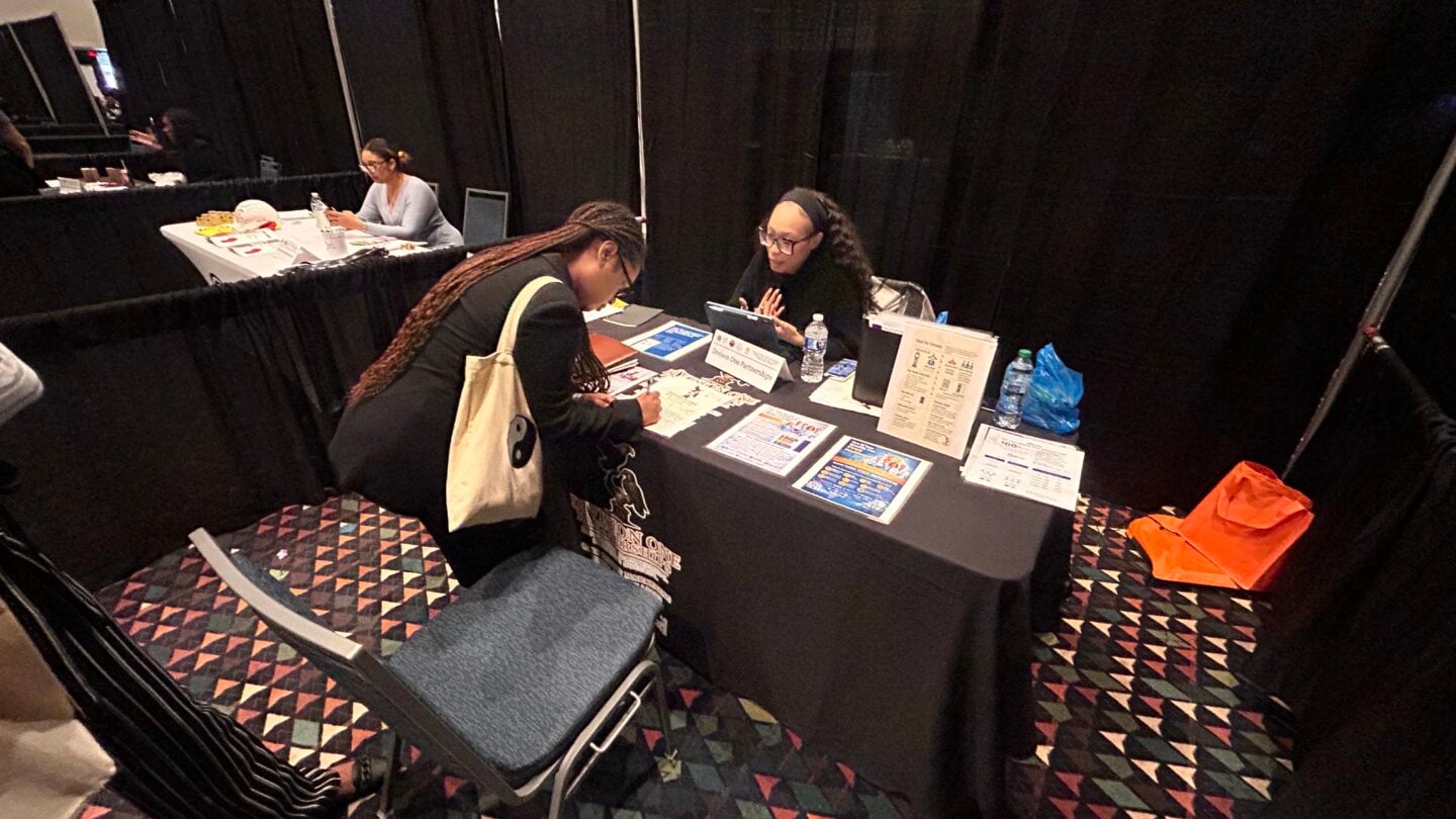 Dos señoras conversan en una mesa de una feria de empleo.