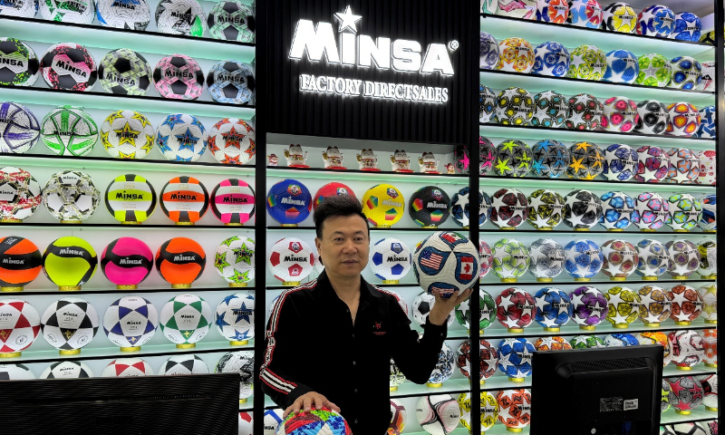 El gerente de Deportes del Minsa, Chen Shaomei, muestra la camiseta de fútbol 2026 en el Mercado de Comercio Internacional de Yiwu.
