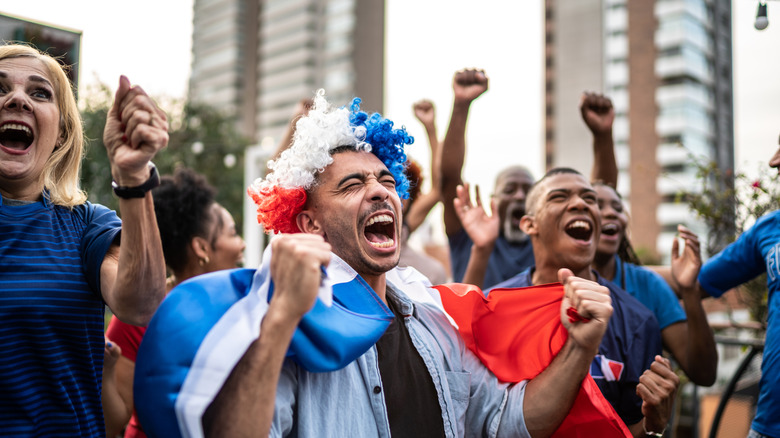 Animando a los fanáticos del fútbol en las calles con coloridas pelucas y banderas.